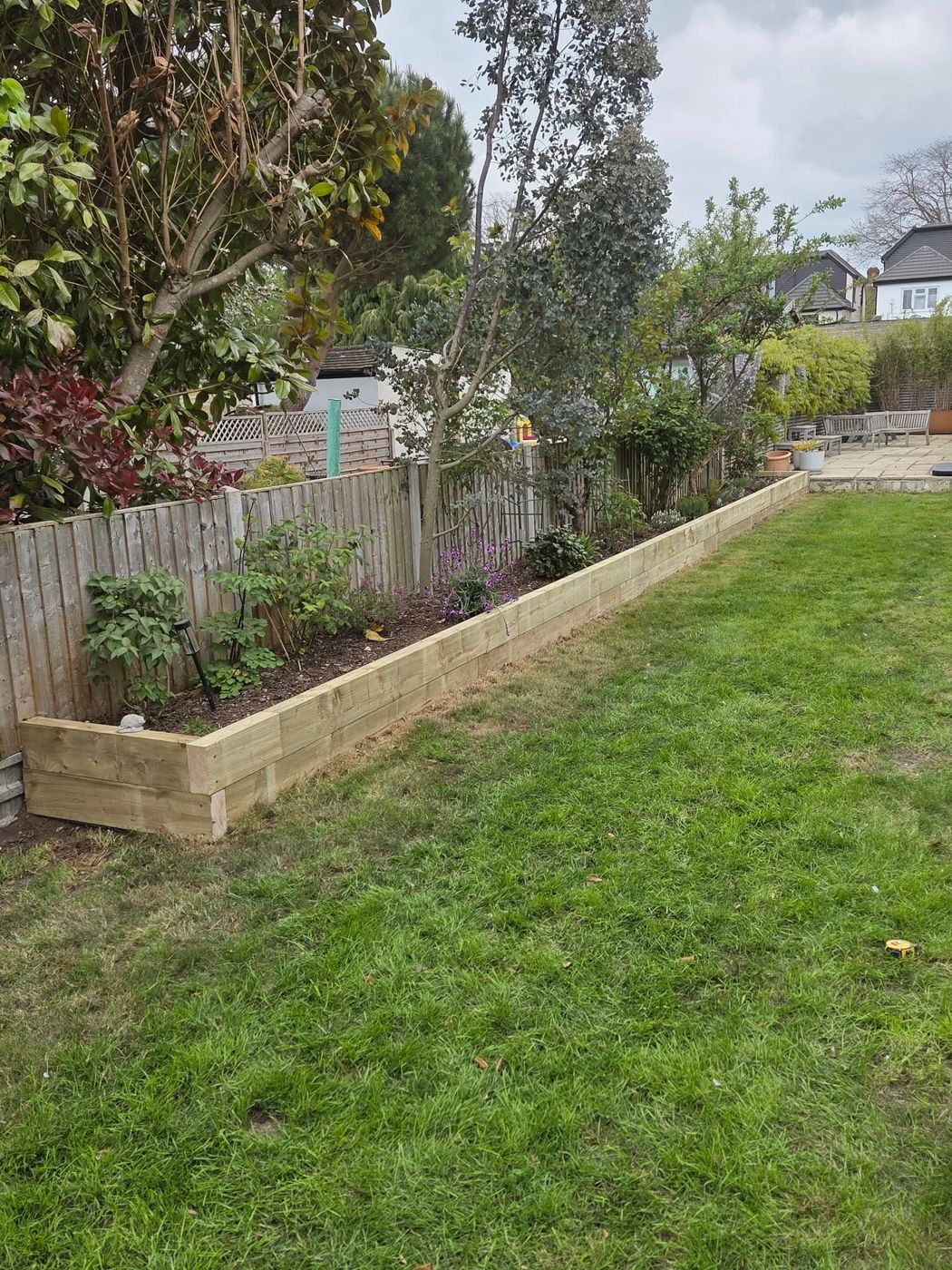 New timber sleeper raised bed built along a garden fence